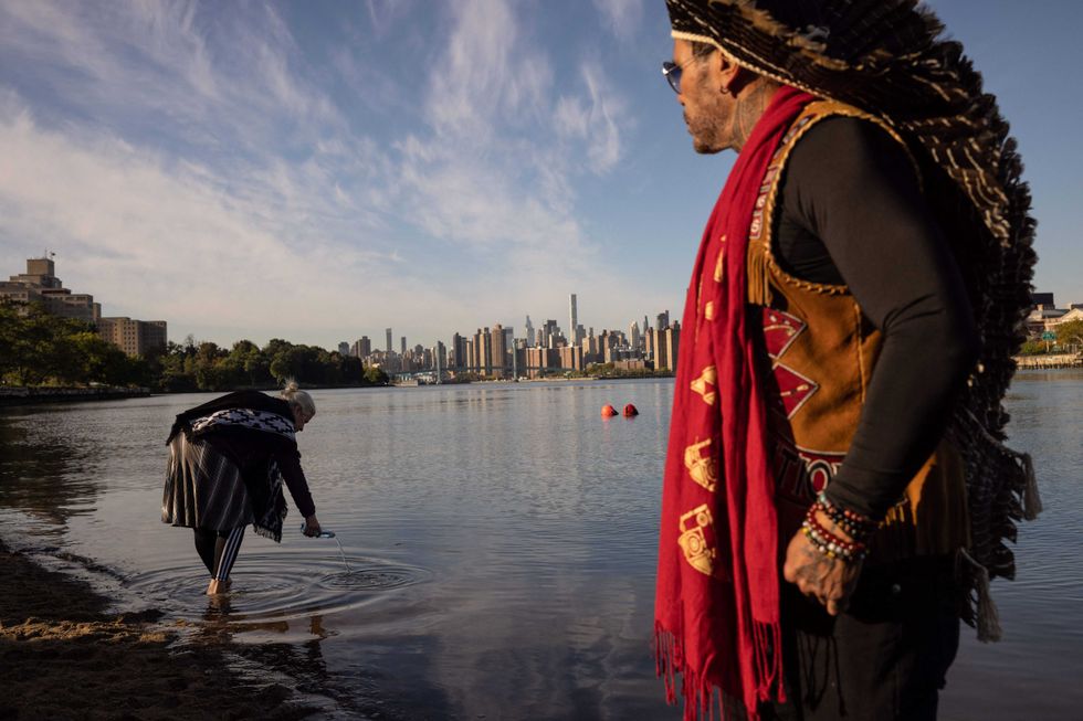 A woman pours water into the East River during an Indigenous Peoples
