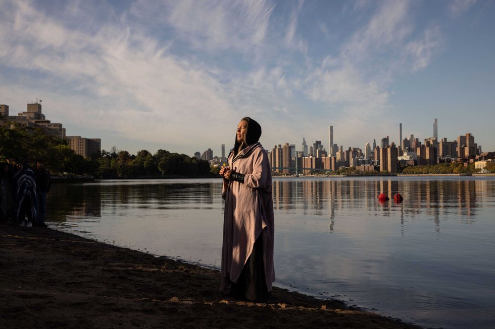 A woman prays while holding a container of water brought from Puerto Rico during an Indigenous Peoples