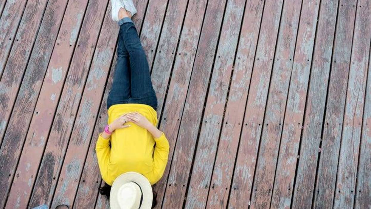 a woman relaxing on the deck with a hat over he head