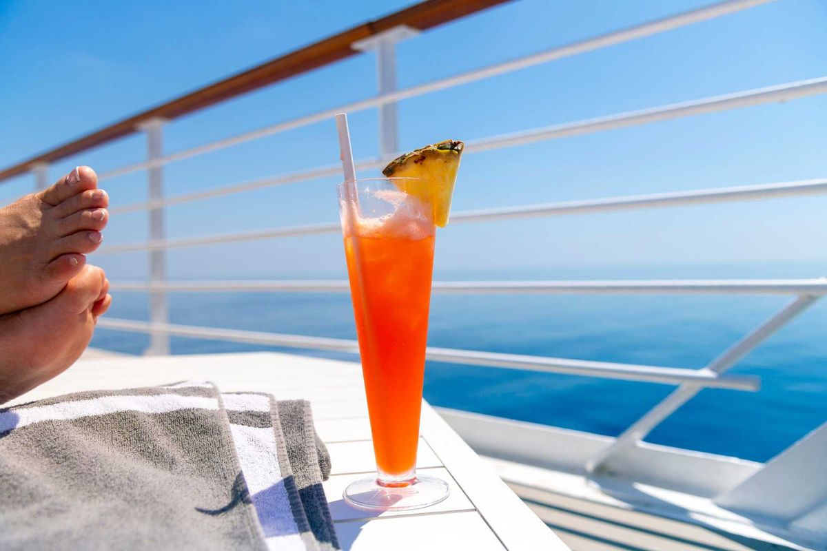 A woman rests her feet on a table on the upper deck of a cruise ship at sea.