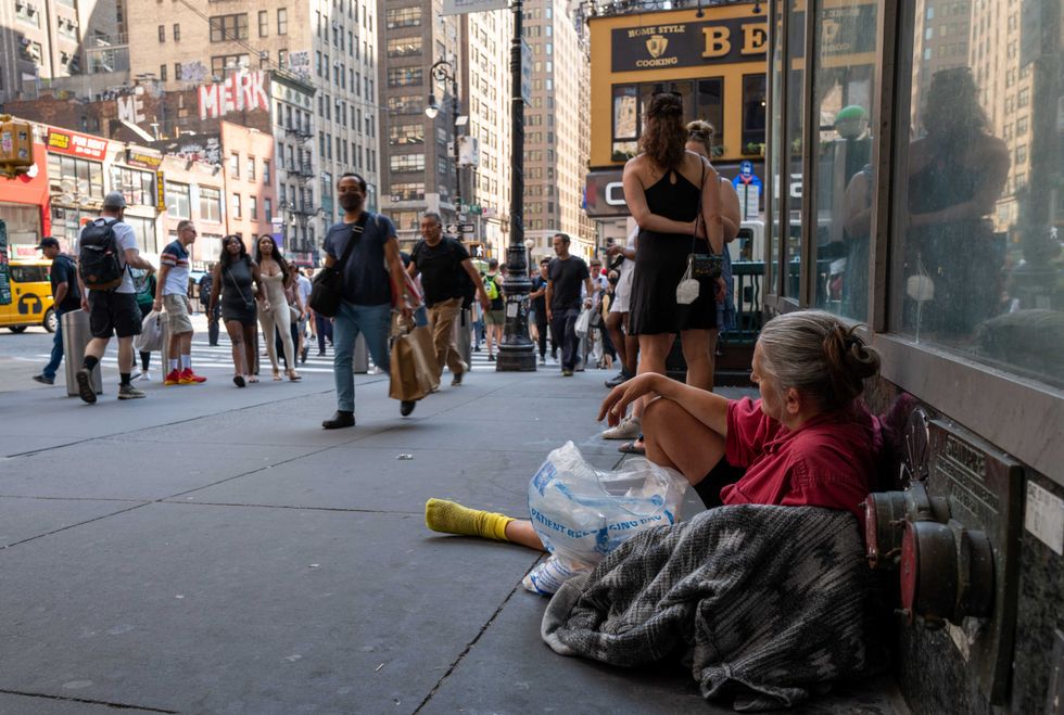 A woman rests on a Manhattan street during a heat wave on July 22, 2022 in New York City.