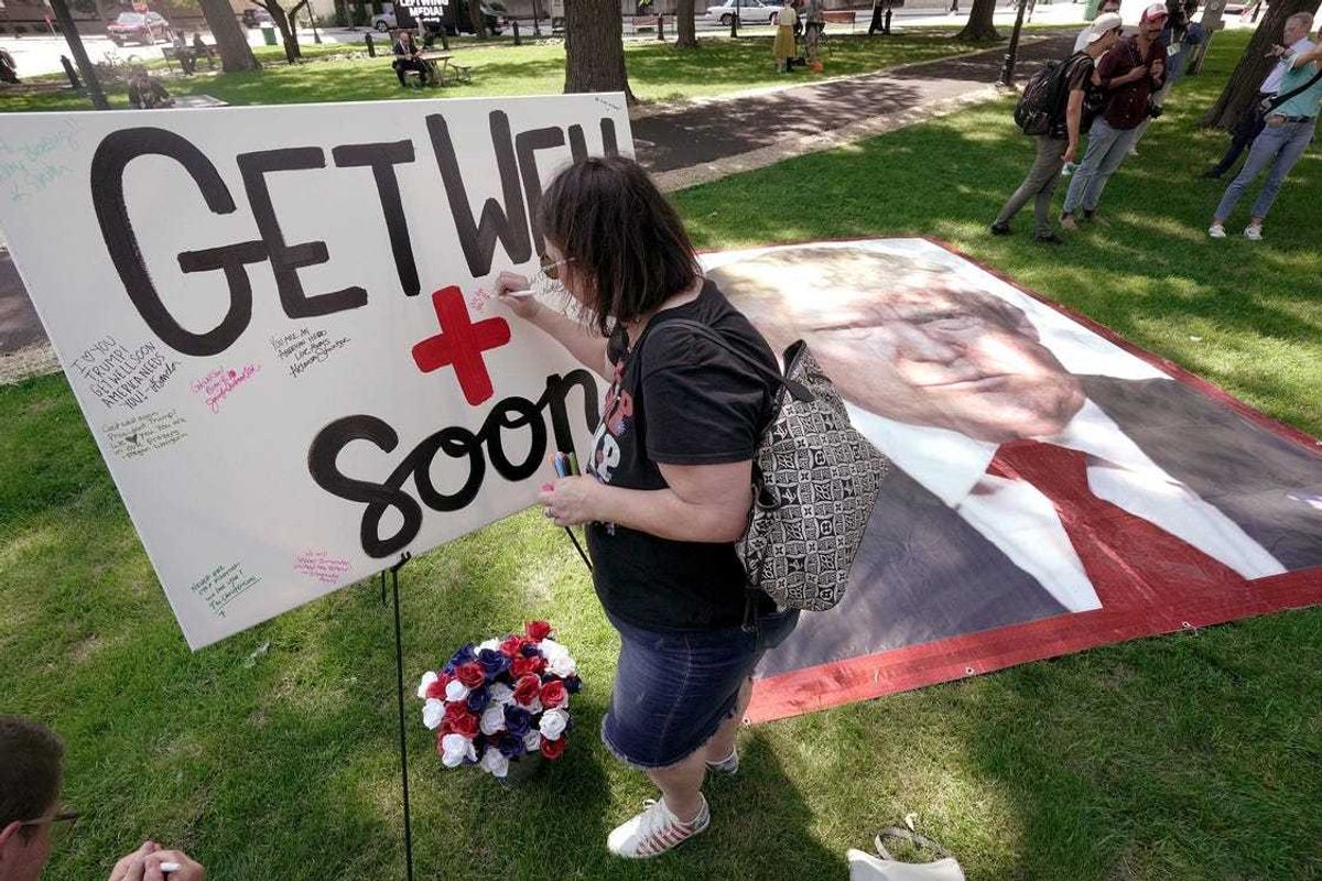 A woman sign a canvas with get well wishes for former President Trump during a Prayer Vigil for America Sunday, July 14, 2024 at Zeidler Union Square in Milwaukee, Wisconsin.