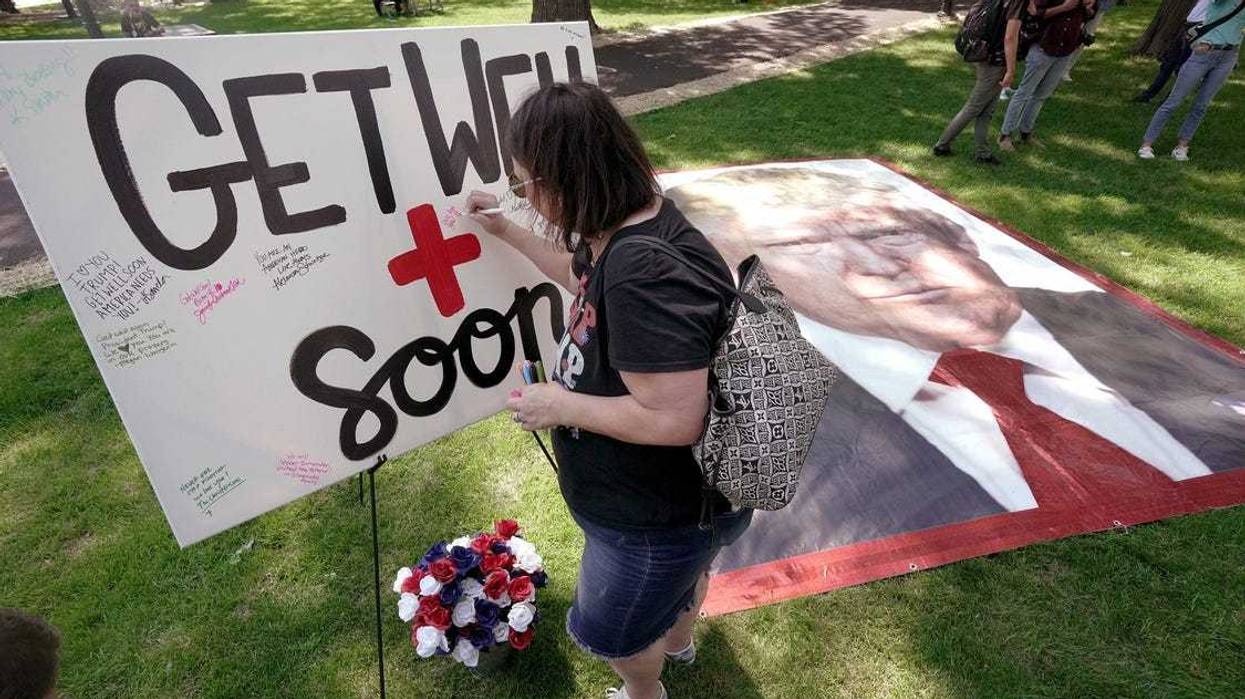 A woman sign a canvas with get well wishes for former President Trump during a Prayer Vigil for America Sunday, July 14, 2024 at Zeidler Union Square in Milwaukee, Wisconsin.