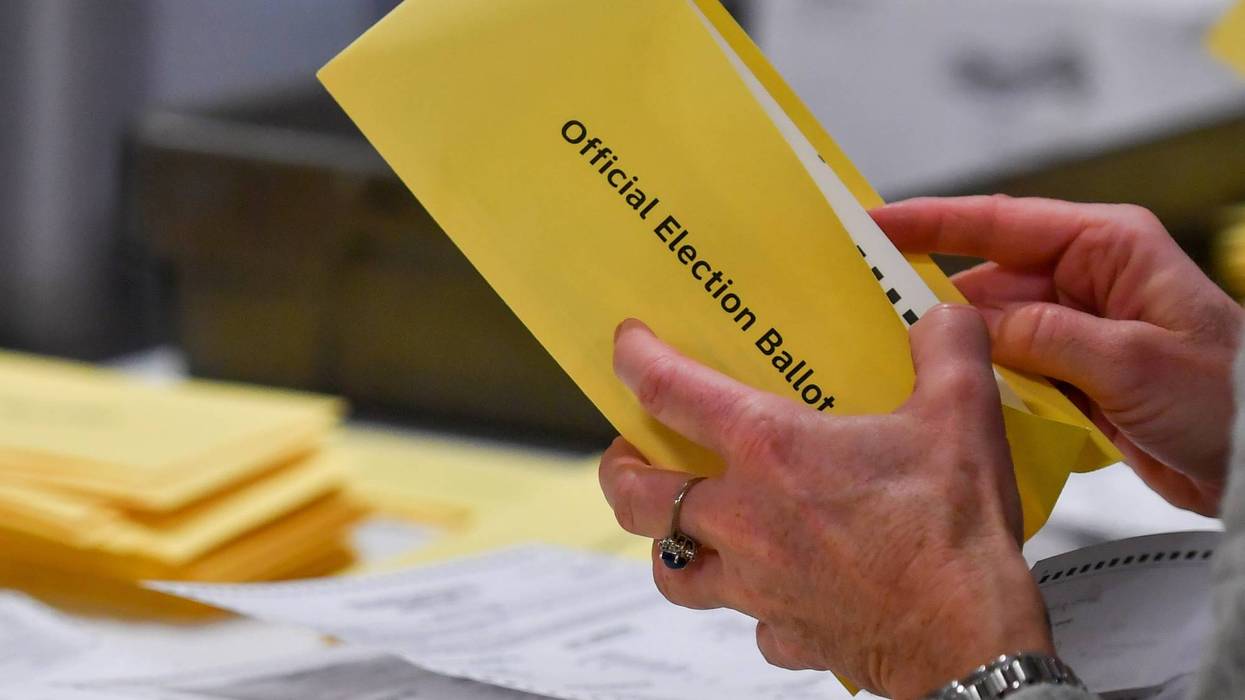 A woman takes a mail-in ballot from an envelope at a polling station in Pennsylvania.