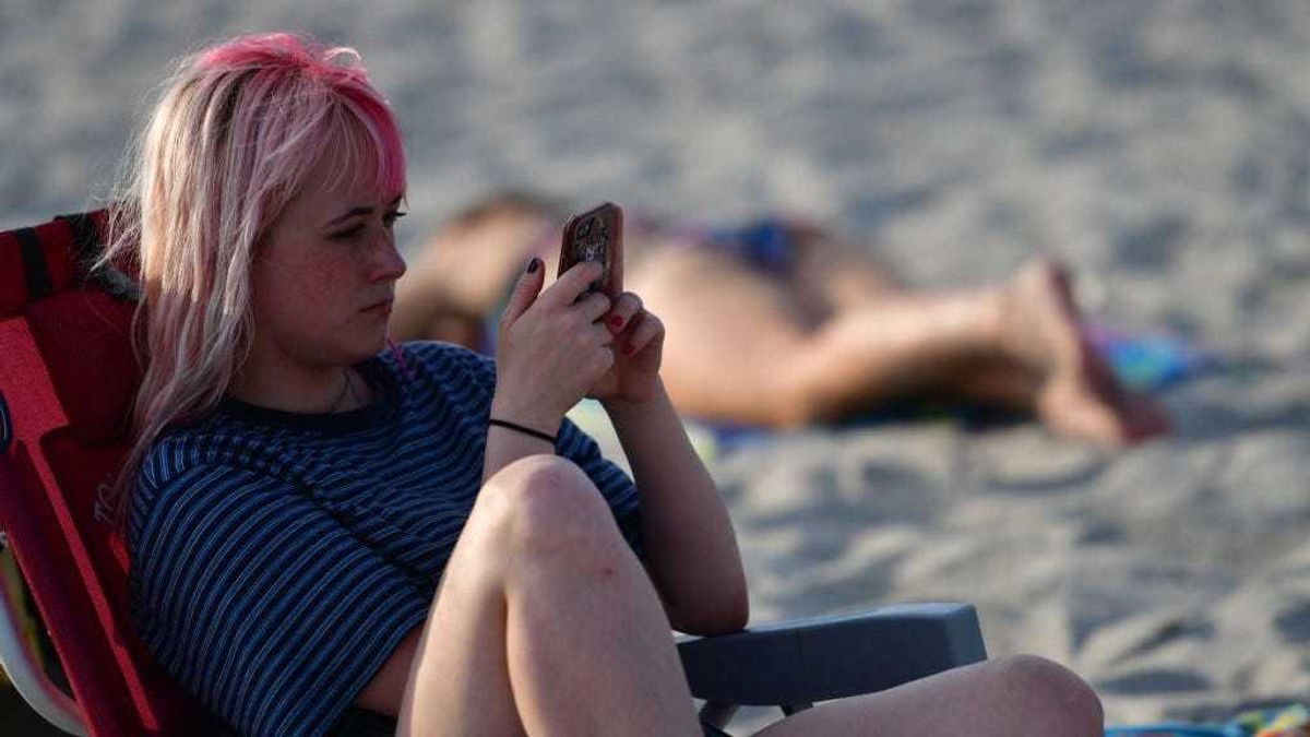 A woman uses her smartphone while sitting in a beach chair on July 3, 2020 in Wildwood, New Jersey.