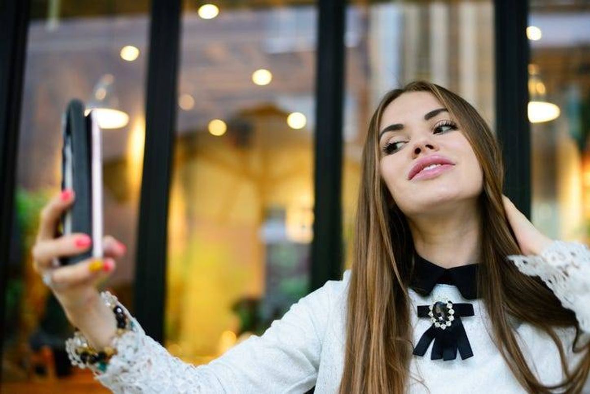 A woman using a smartphone to take a selfie.
