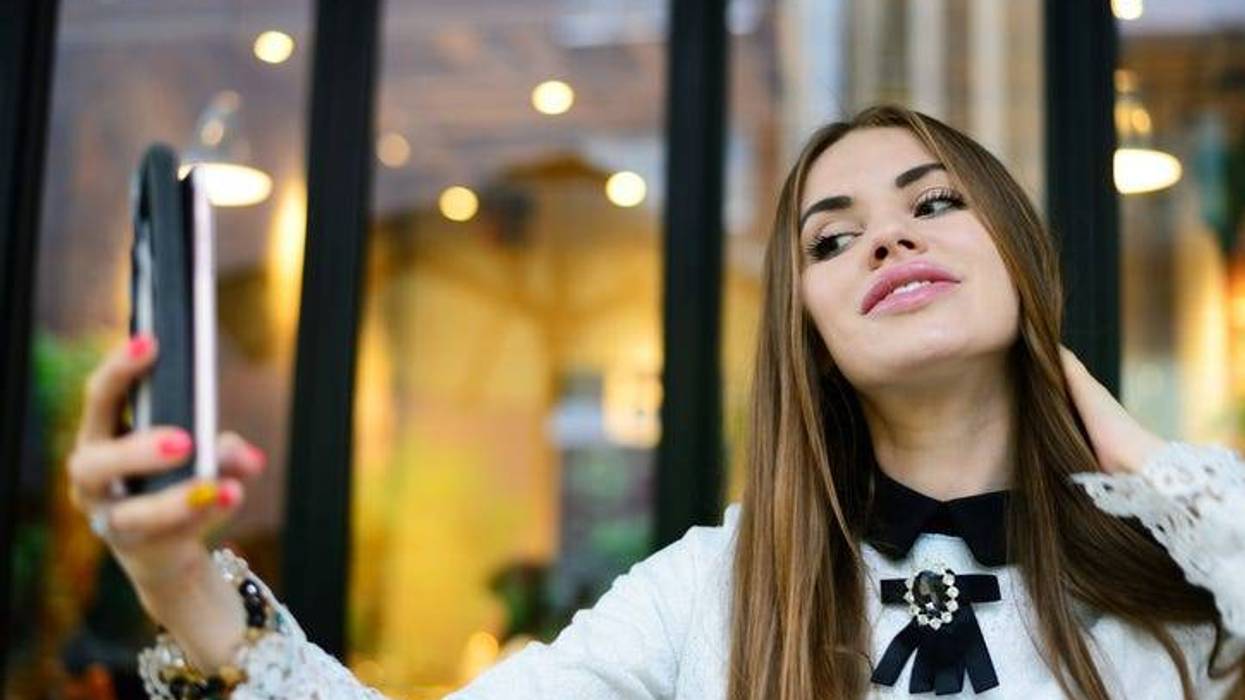 A woman using a smartphone to take a selfie.