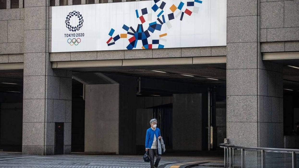 A woman walks beneath a Tokyo 2020 Olympics banner on March 19, 2020 in Tokyo, Japan.