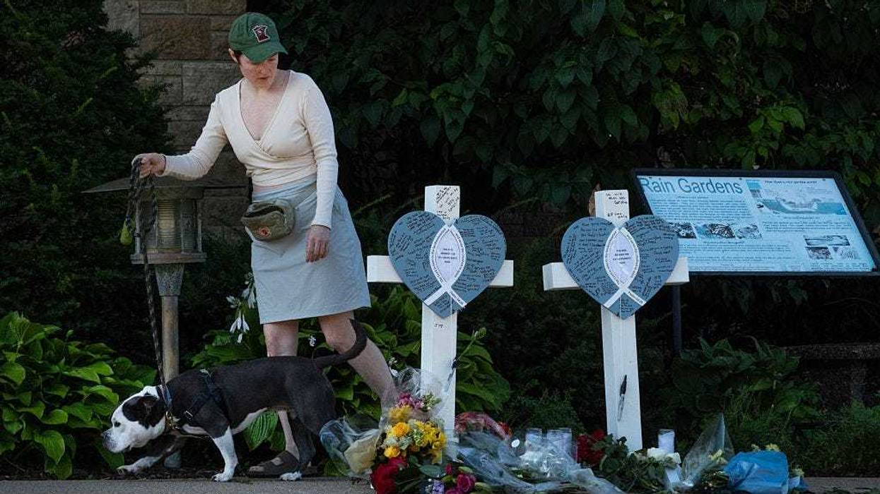 A woman walks her dog past a memorial to yesterday's shooting victims in front of Annunciation Catholic Church on August 28, 2025 in Minneapolis, Minnesota.