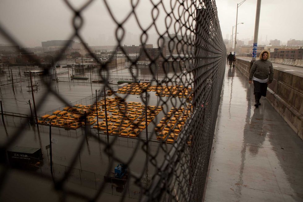 A woman walks on an overpass above a fleet of taxis submerged in water in Hoboken, New Jersey, on Oct. 30, 2012
