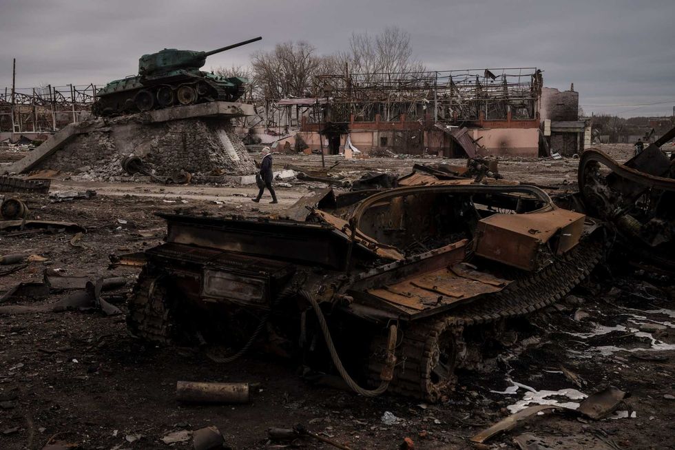 A woman walks past a destroyed tank in the town of Trostsyanets, Ukraine, Monday, March 28, 2022. Trostsyanets was recently retaken by Ukrainian forces after being held by Russians since the early days of the war