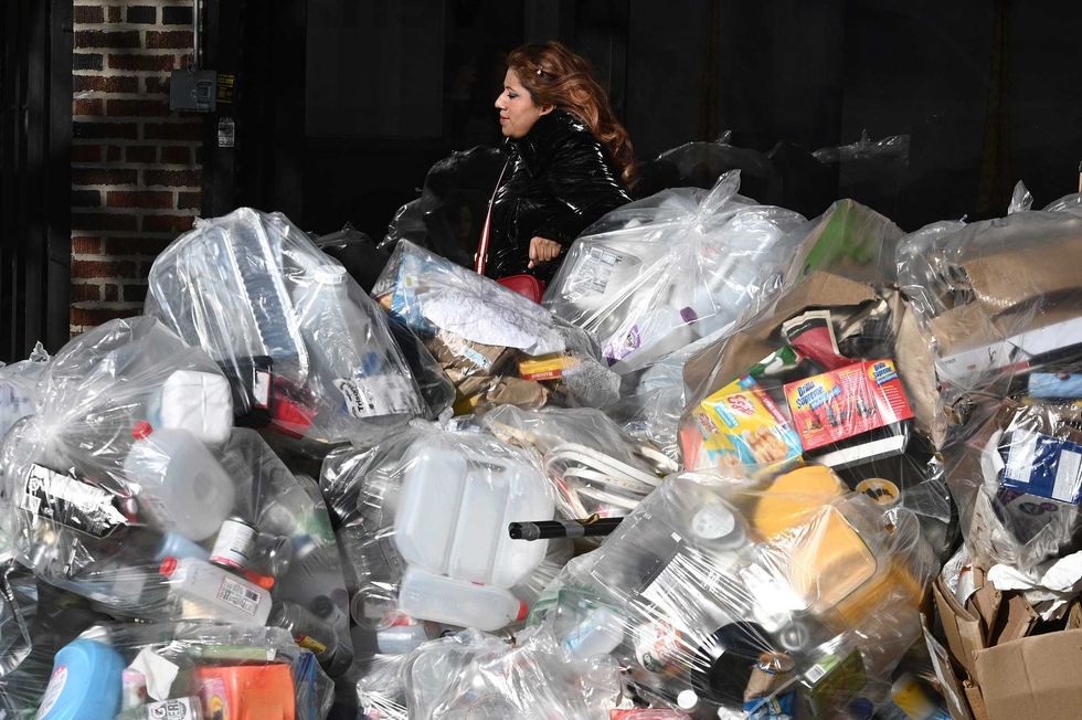 A woman walks past a pile of garbage along 43rd Avenue in Queens on Nov. 3, 2021