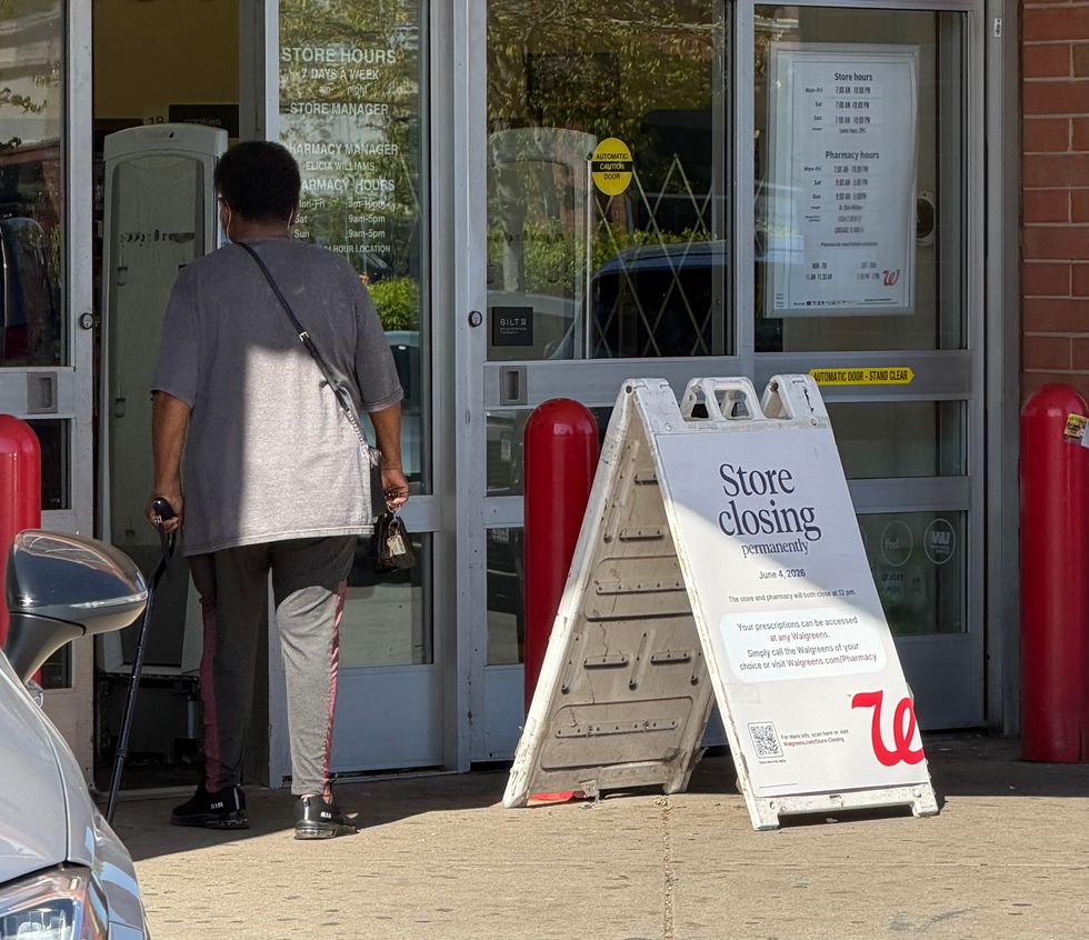 A woman walks past a sign in front of the Walgreens store in Chicago's Chatham neighborhood that announces the store's plan to close June 4.