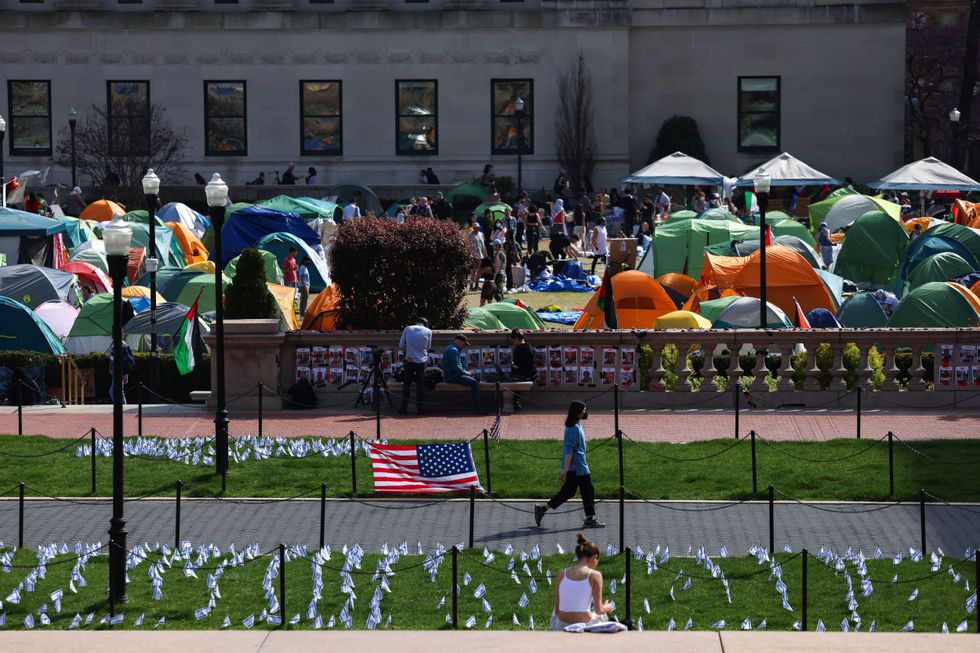 A woman walks past Israeli and US flags alongside portraits of Israelis taken hostage by Hamas in front of the pro-Palestinian encampment at Columbia University on April 28, 2024