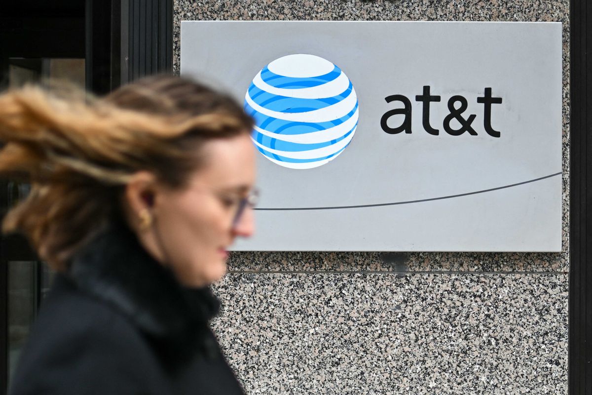 A woman walks past signage for AT&T in Washington, DC, on Feb. 22, 2024.