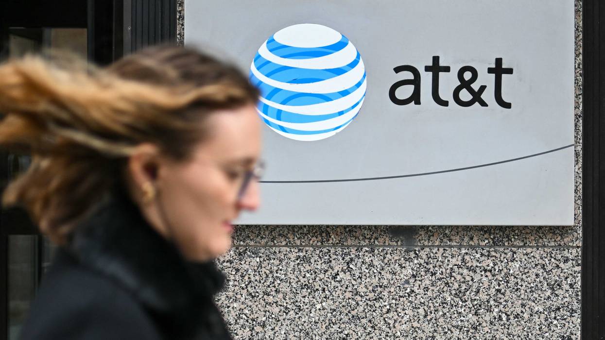 A woman walks past signage for AT&T in Washington, DC, on Feb. 22, 2024.