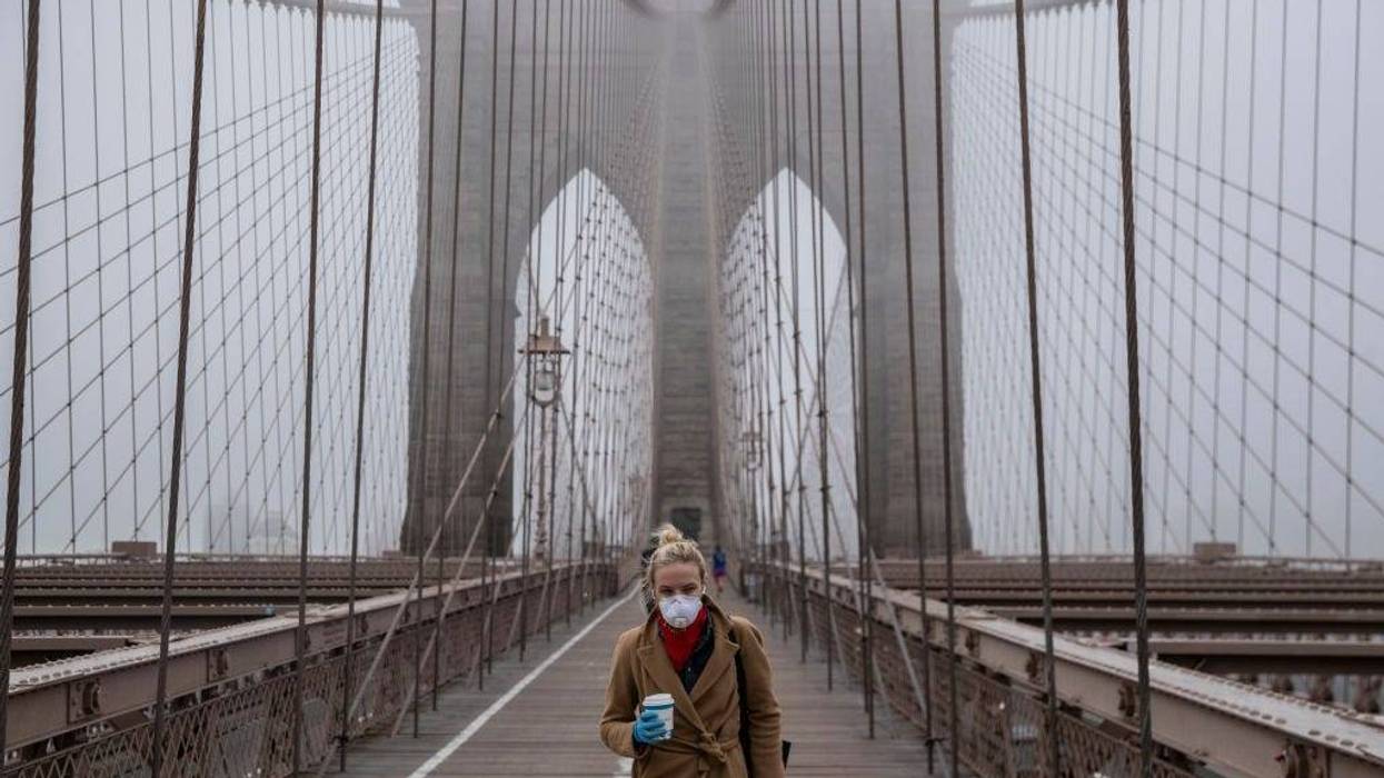 A woman wearing a mask walks the Brooklyn Bridge in the midst of the coronavirus (COVID-19) outbreak on March 20, 2020 in New York City.