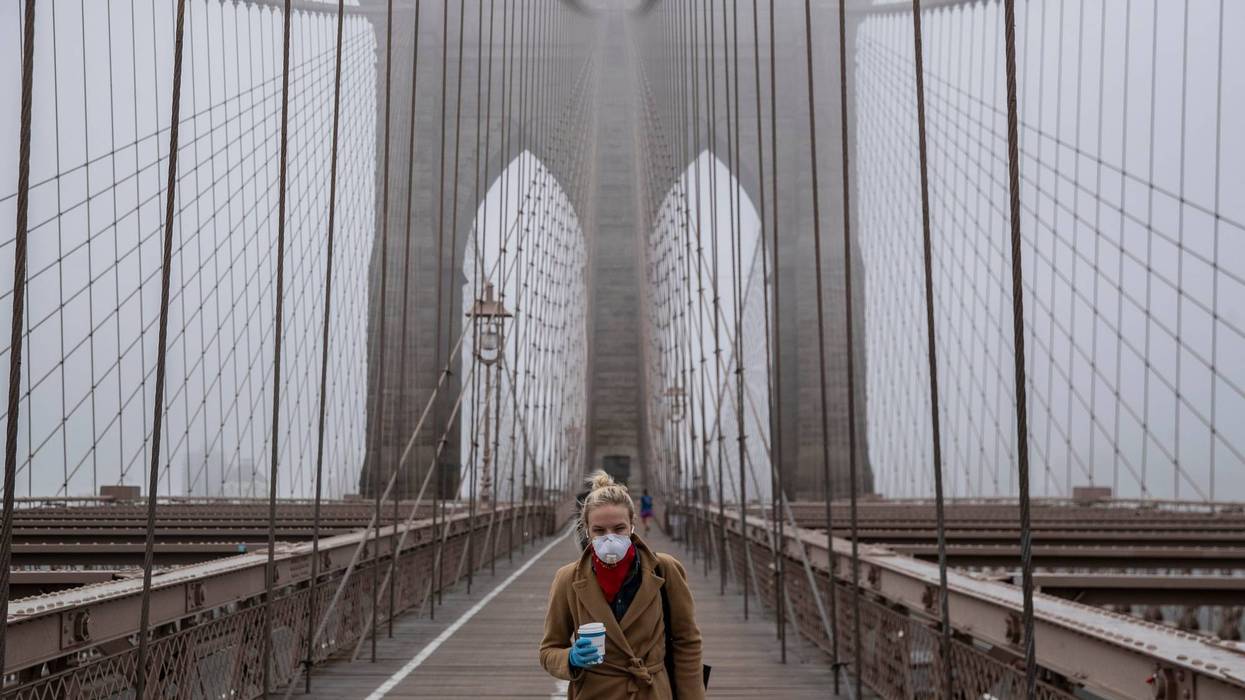 A woman wearing a mask walks the Brooklyn Bridge in the midst of the coronavirus (COVID-19) outbreak on March 20, 2020 in New York City.