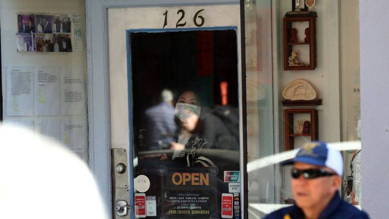 A woman wears a surgical mask as she looks out of a window as U.S. Speaker of the House Rep. Nancy Pelosi (D-CA) tours San Francisco's Chinatown on February 24, 2020 in San Francisco, California.