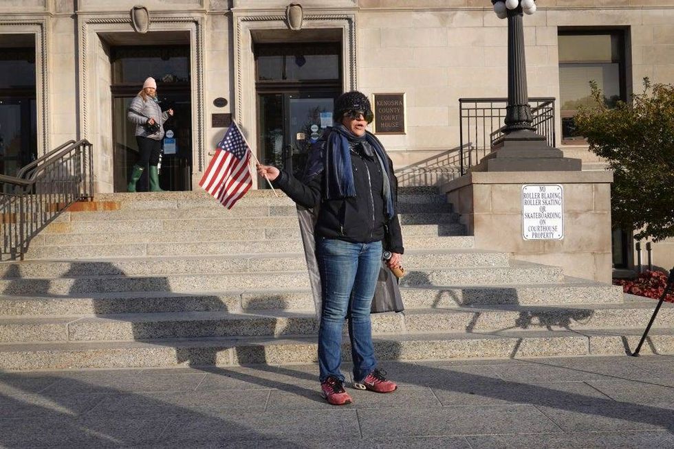 A woman who identified herself as a "patriot" demonstrates outside the Kenosha County Courthouse as jury selection in the trial of Kyle Rittenhouse begins on November 01, 2021 in Kenosha, Wisconsin. Rittenhouse shot three demonstrators, killing two of them, during a night of unrest that erupted in Kenosha after a police officer shot Jacob Blake seven times in the back while police attempted to arrest him in August 2020. Rittenhouse, from Antioch, Illinois, was 17 at the time of the shooting and armed with an assault rifle. He faces counts of felony homicide and felony attempted homicide.