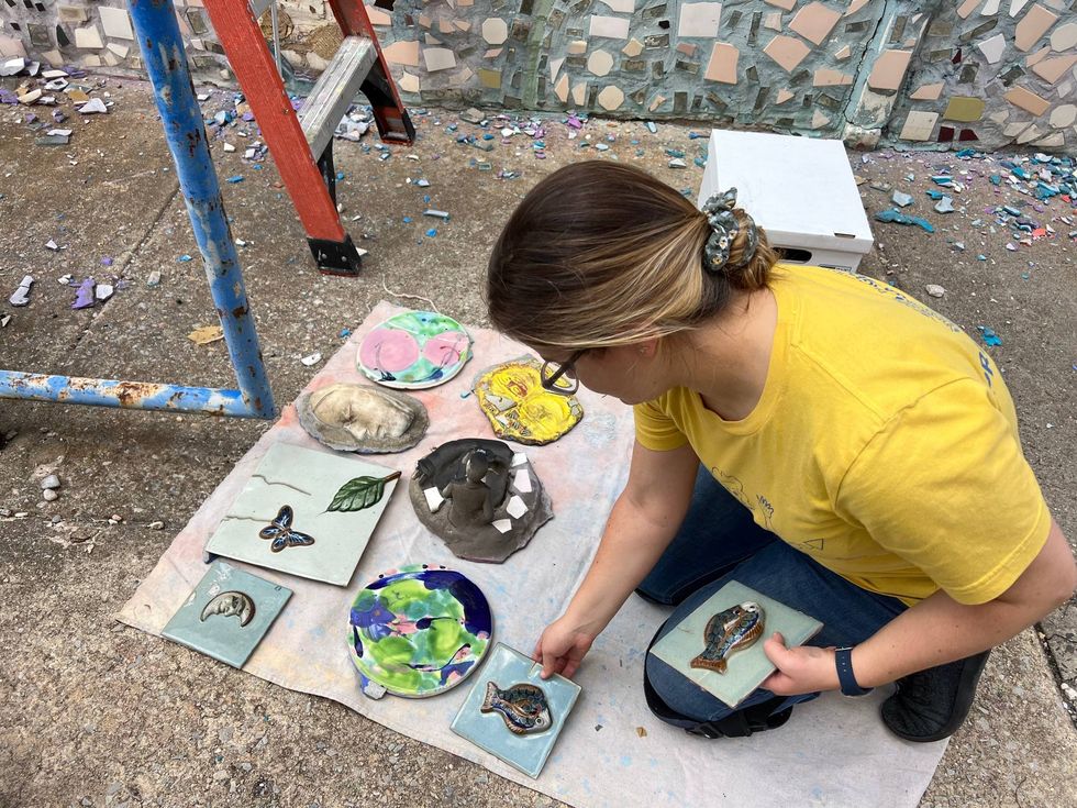 A woman works to take down mosaic tiles from the Painted Bride Art Center