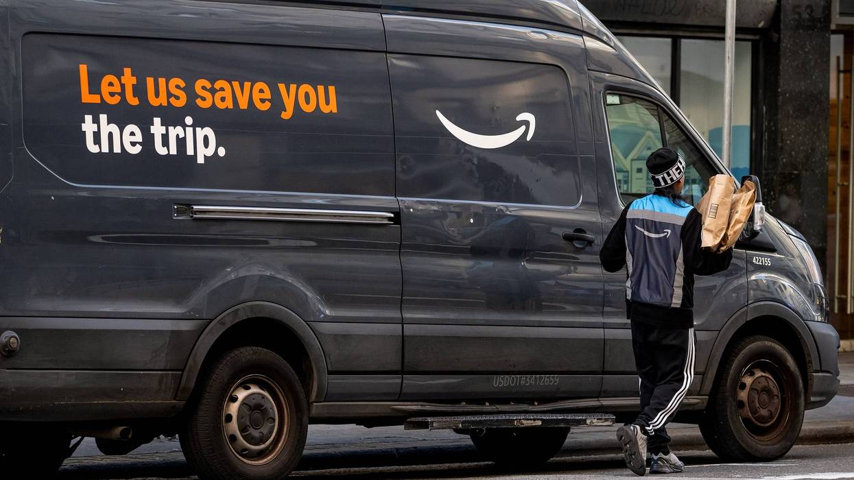 A worker carries packages near an Amazon delivery vehicle in San Francisco, California, on Feb. 2, 2026.