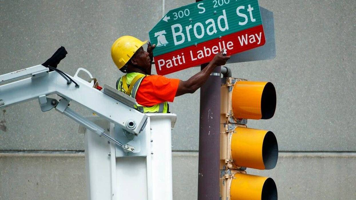 A worker hangs a street sign before a ceremony honoring singer Patti LaBelle, Tuesday, July 2, 2019, in Philadelphia. A stretch of Broad Street, between Locust and Spruce Streets, will be renamed "Patti LaBelle Way."