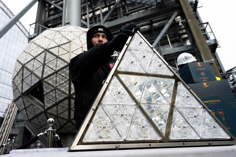 A worker holds up a panel of Waterford Crystal triangles atop One Times Square on Dec. 27, 2022