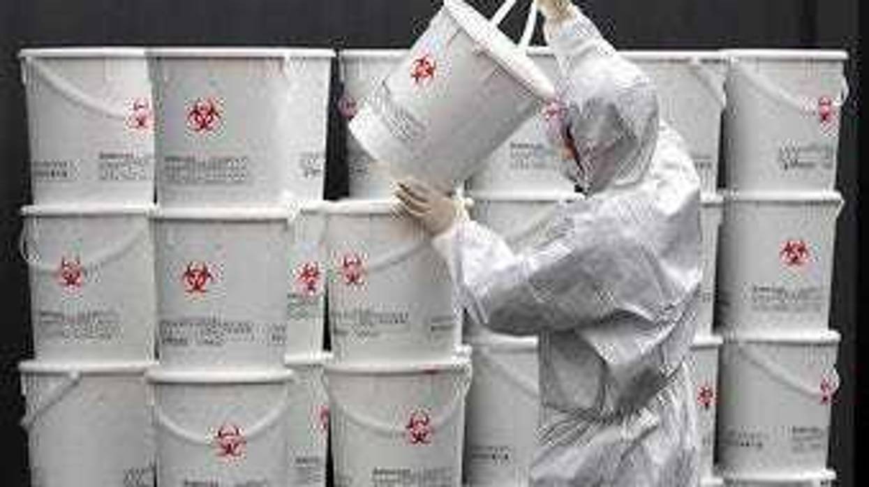 A worker in protective gear stacks plastic buckets containing medical waste from coronavirus patients at a medical center in Daegu, South Korea, Monday, Feb. 24, 2020. (Lee Moo-ryul/Newsis via AP)