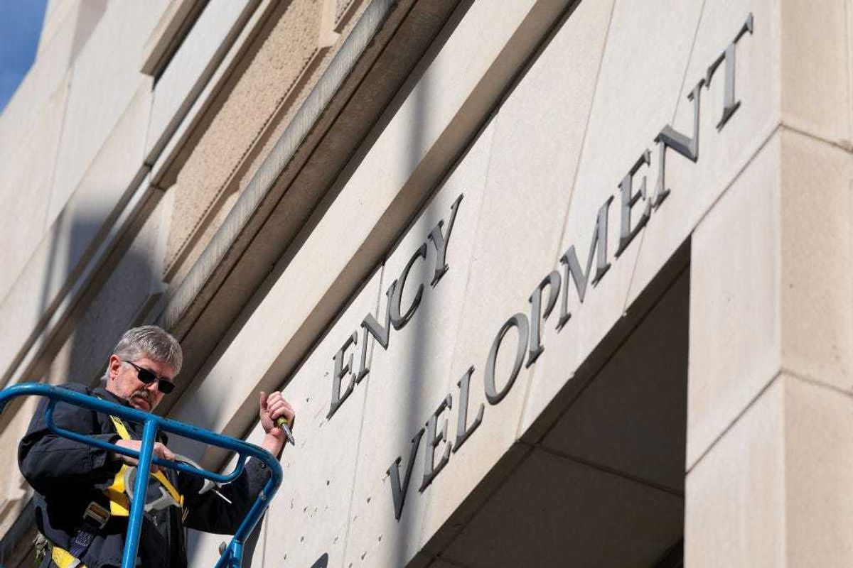 A worker removes the U.S. Agency for International Development sign on their headquarters on February 07, 2025 in Washington, DC.