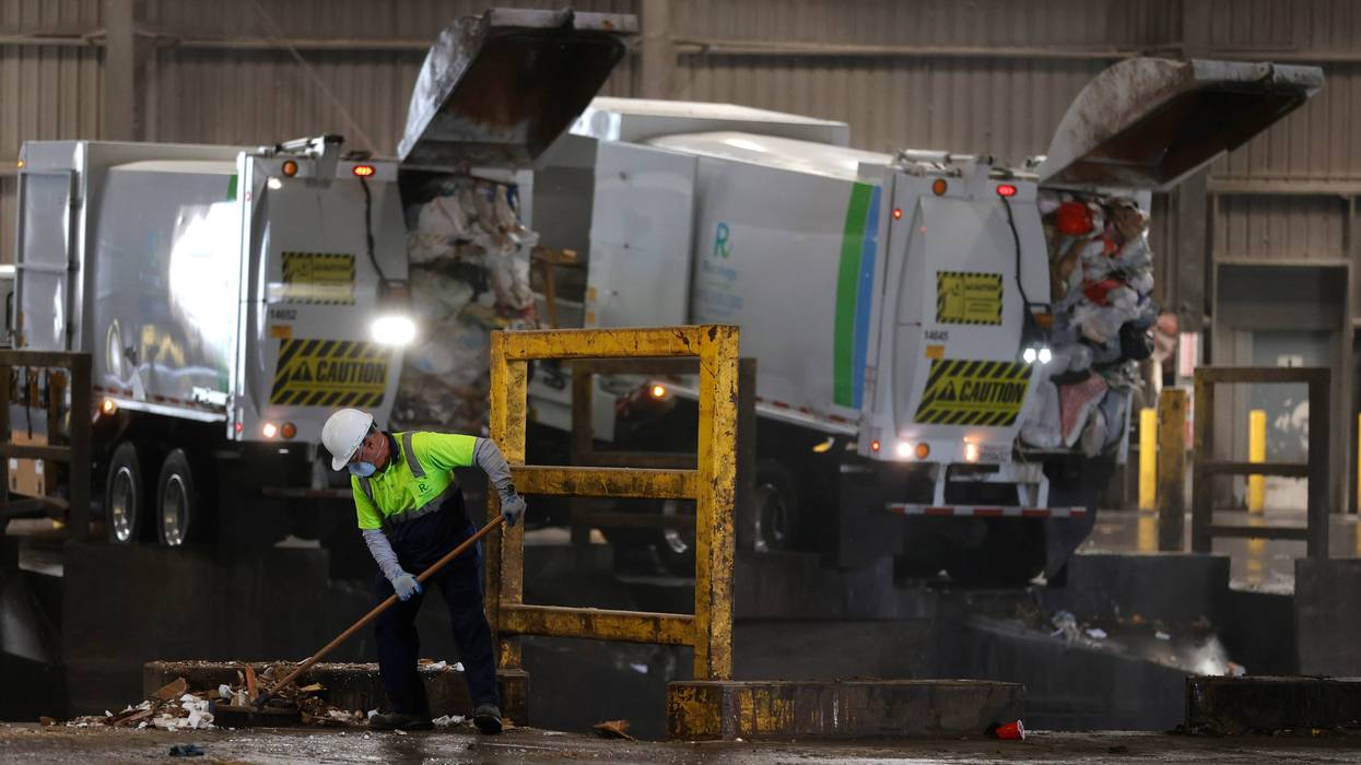 A worker sweeps garbage into a trash pit at Recology on April 2, 2021 in San Francisco, California.