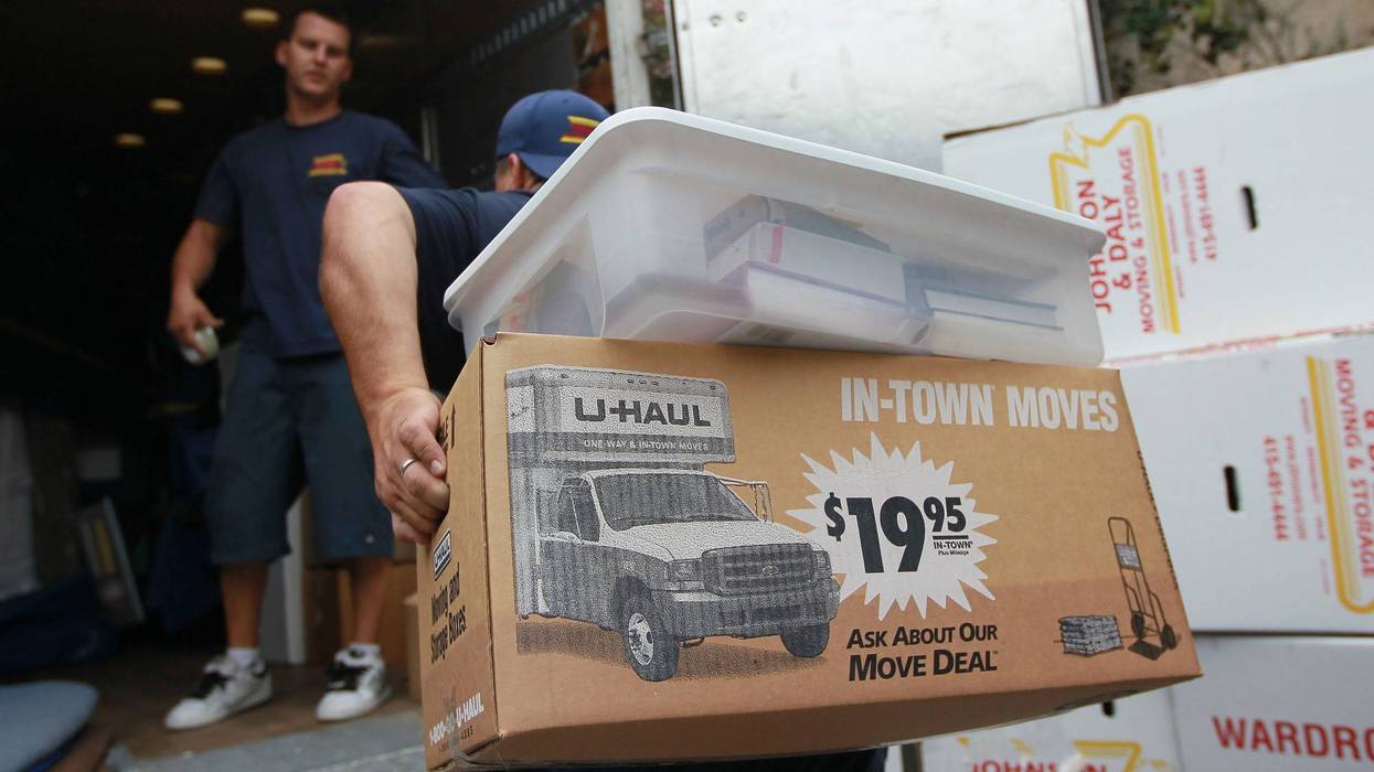 A worker with Johnson and Daly Moving and Storage carries boxes to a truck while moving a family.