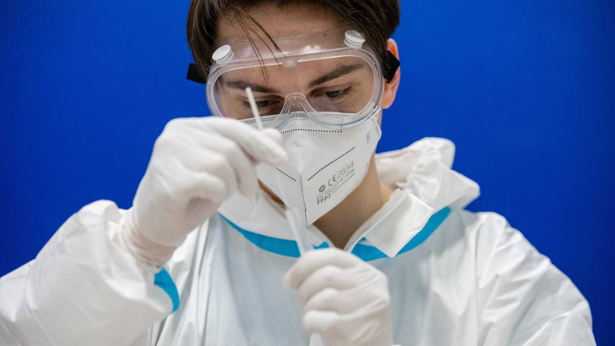A worker with the Arbeiter Samariter Bund charity administers rapid antigen COVID-19 tests to high school students at the Ehrenfried Walther von Tschirnhaus Gymnasium high school on the second day after students returned to class during the coronavirus pandemic on March 16, 2021 in Dresden, Germany. Schools have been reopening across Germany, starting with the youngest pupils and more recently adding older students. Frequent COVID testing is part of the reopening concept, though not all regions have access to sufficient numbers of test kits. Health authorities warn however that the recent rise in COVID infections could be in part fuelled by the B117 variant spreading among children. (Photo by Jens Schlueter/Getty Images)