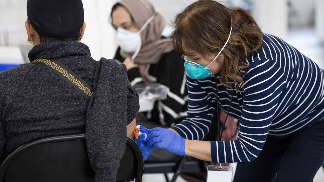A worker with the Chicago Department of Public Health gives the measles-mumps-rubella vaccine to an individual at the migrant shelter for new arrivals in Pilsen.