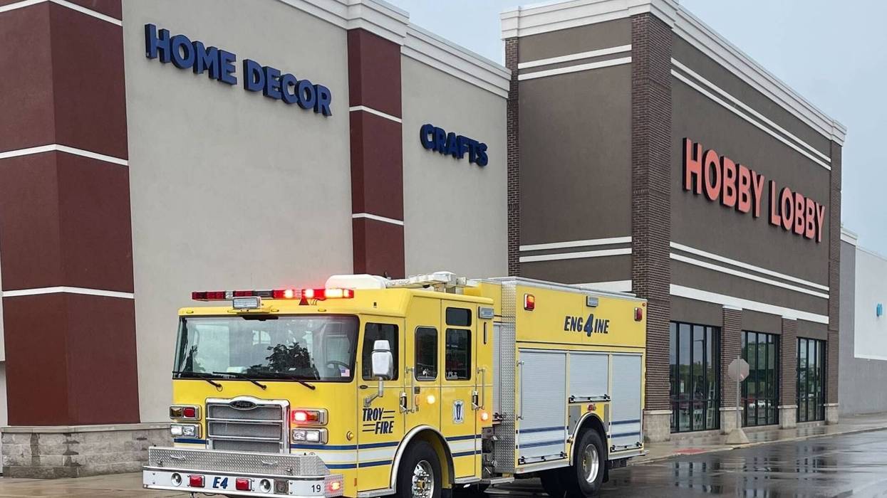 A yellow fire truck is parked near the curb of a Hobby Lobby