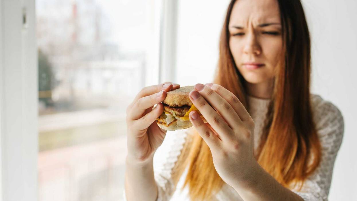 A young girl shows that she does not like a burger.Conceptual image of refusal from unhealthy eating. Fast food.