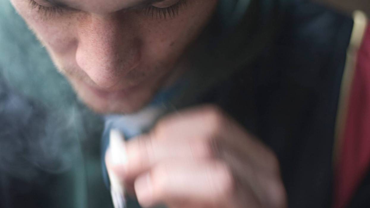 A young person smokes a marijuana joint.