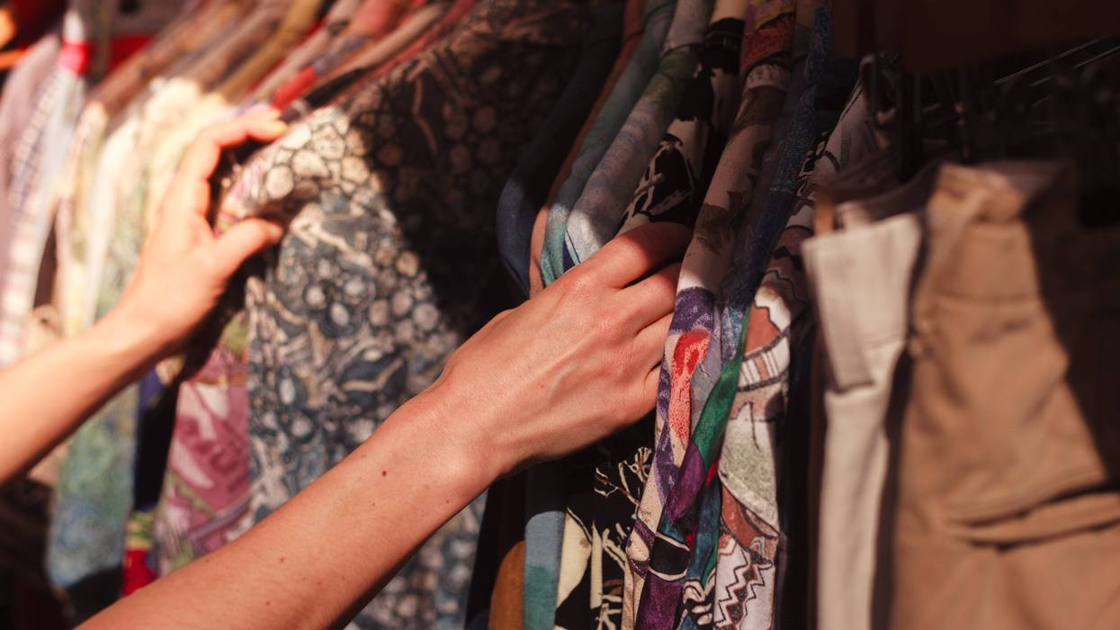 A young woman browses a rail of clothes at a street market.