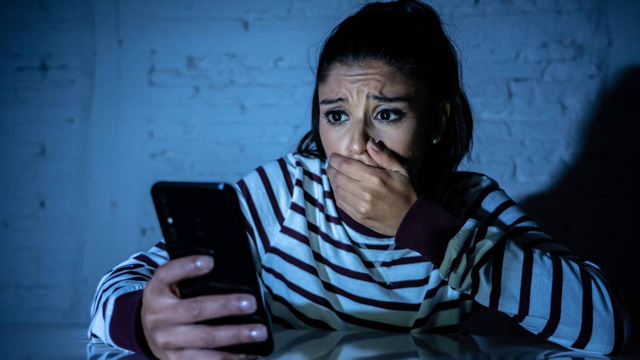 A young woman expresses shock and disturbance at her phone.