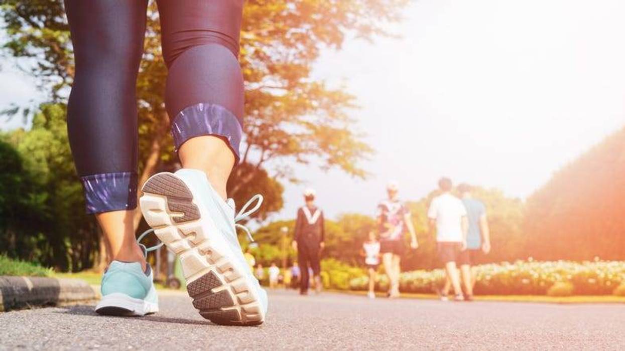 A young woman's legs walking with group of people exercising in the city public park in morning