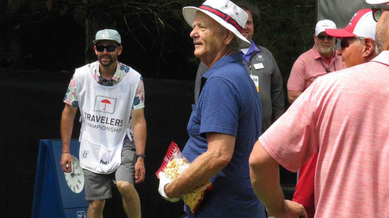 Actor Bill Murray prepares to playfully toss a bag of kettle corn to fans at the Travelers Pro-Am, 6/21/23 in Cromwell
