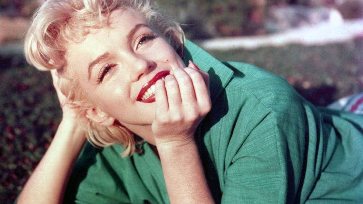 Actress Marilyn Monroe poses for a portrait laying on the grass in 1954 in Palm Springs, California.