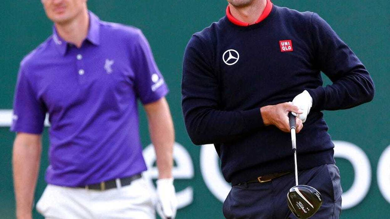 Adam Scott, of Australia, watches his shot off the first tee with Justin Rose, of England