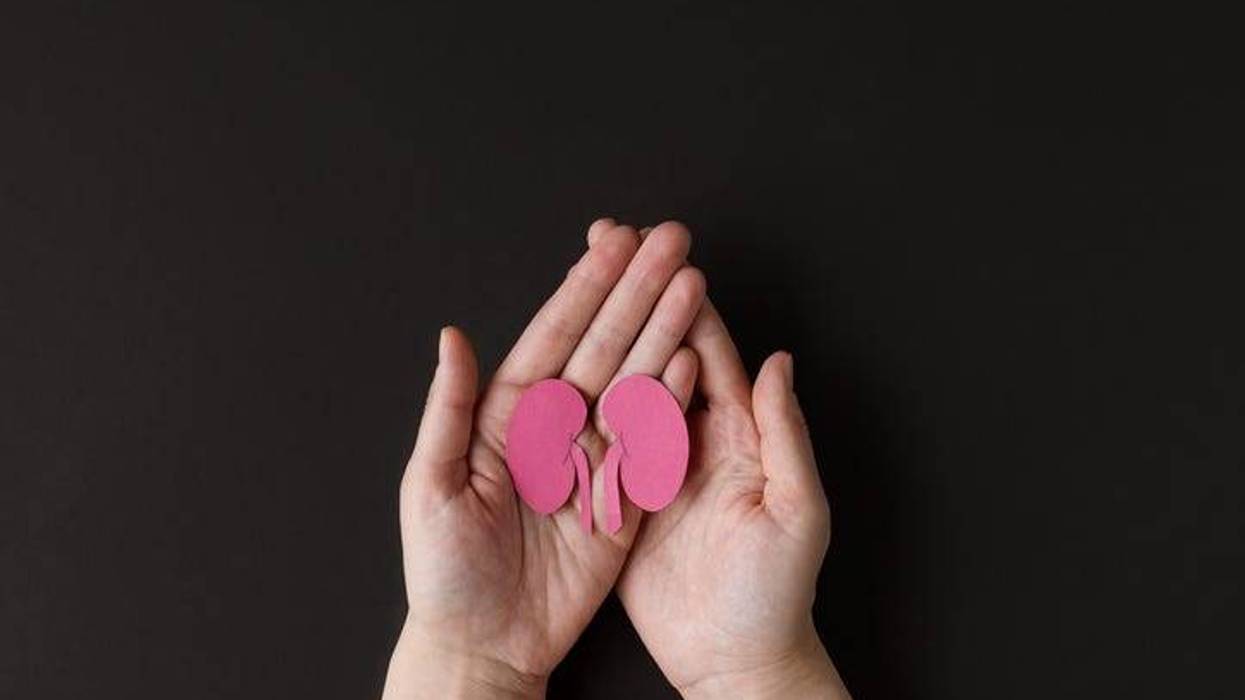Adult hands holding kidney shaped paper on black background.