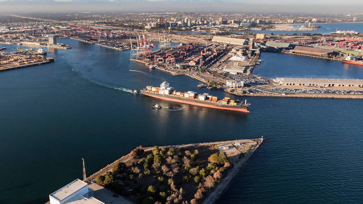 Aerial view of container cargo ship leaving Long Beach Harbor in Los Angeles County California.