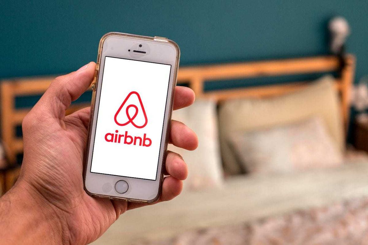 Airbnb on phone in front of a bed