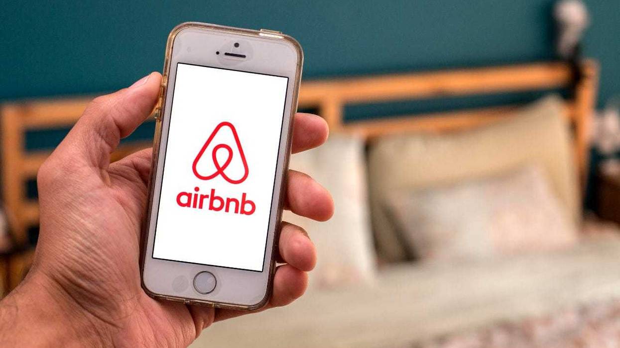 Airbnb on phone in front of a bed