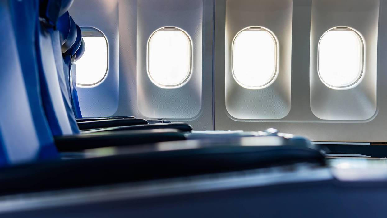 Airplane windows and empty blue business class seat, Interior of modern aircraft cabin.