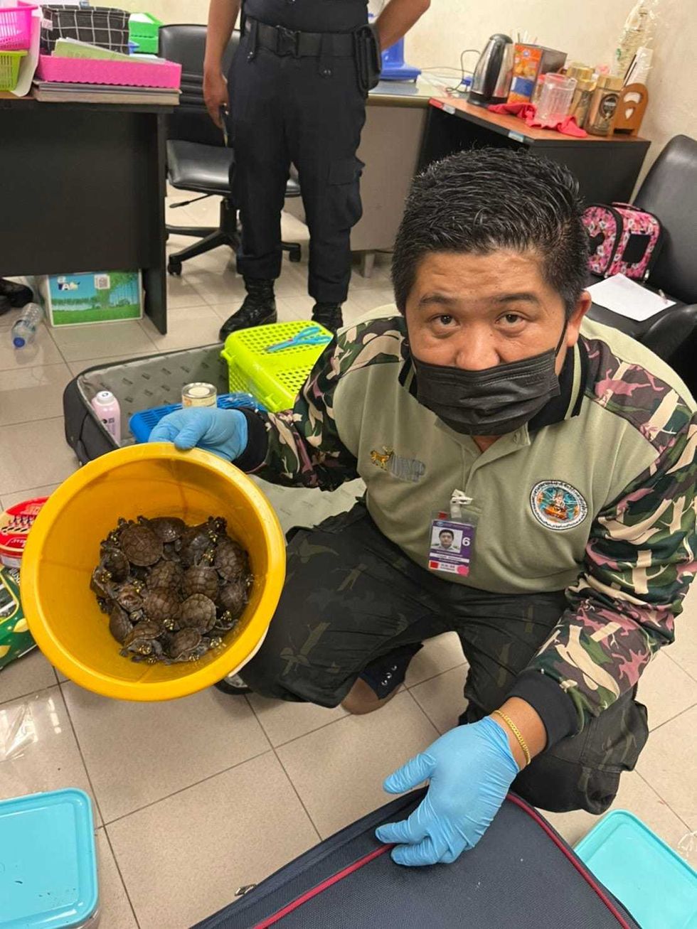 Airport officials holding a bucket full of turtles confiscated from the women.