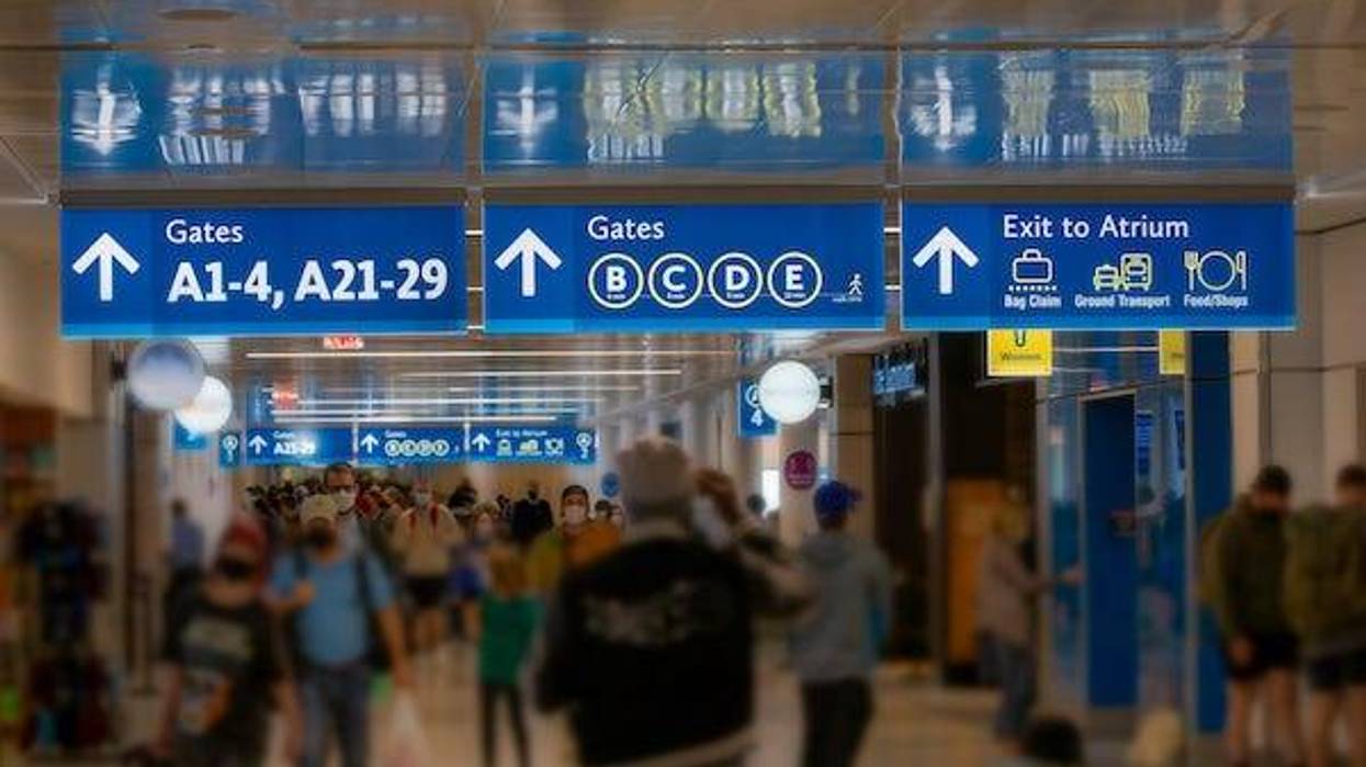 Airport Terminal signs with rushing commuters